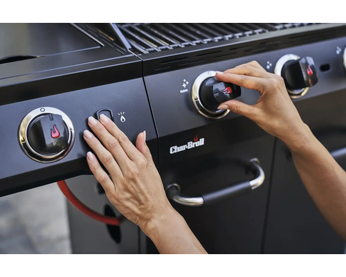 Gros plan d''un barbecue à gaz Char-Broil avec des mains actionnant le bouton d''allumage et le bouton rotatif.