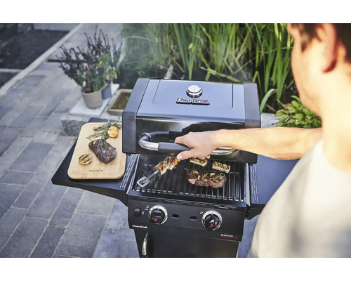 Barbecue à gaz Char-Broil avec des aliments grillés et un homme qui actionne le barbecue