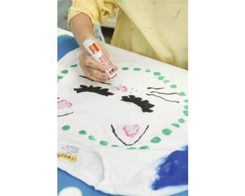 Person bemalt ein T-Shirt mit einem Glitzerstift.