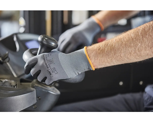Une personne utilise une machine avec des gants de travail gris.