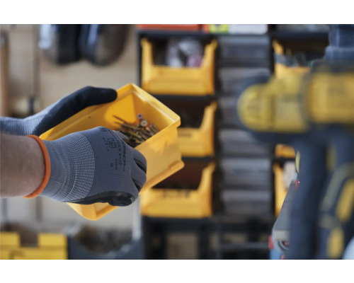 Une personne tient une boîte d''assortiment jaune avec des vis et porte des gants.