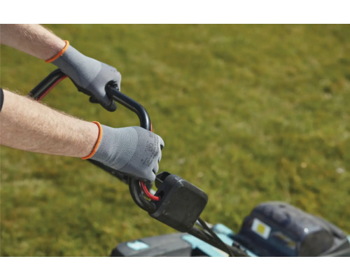 Personne utilisant une tondeuse à gazon avec des gants de travail.