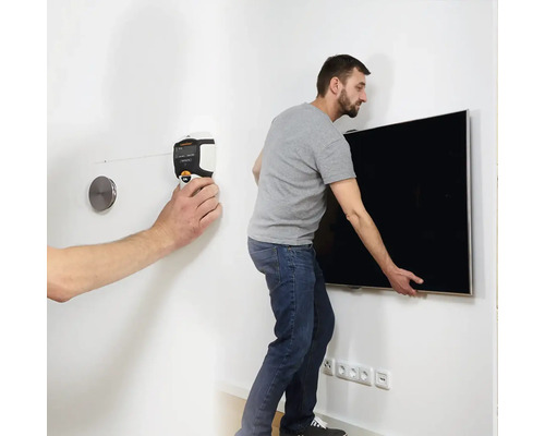 Mann montiert mit einem Nivelliergerät einen Fernseher an einer Wand.