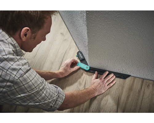 Ein Mann verwendet eine Anreißlehre von Wolfcraft zum Verlegen von Laminat.