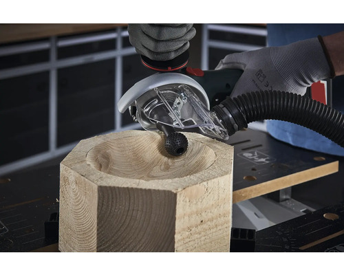 Une personne forme un bol dans un morceau de bois avec une fraise