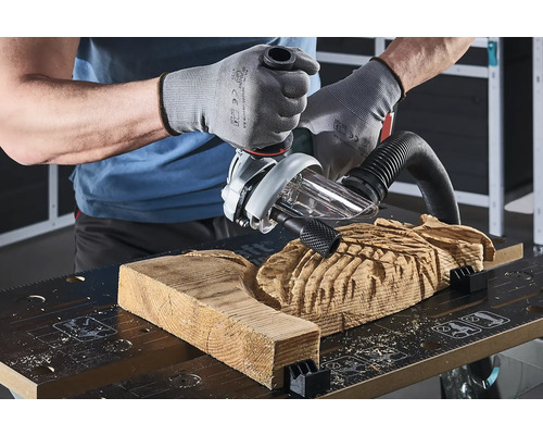 Un artisan travaille une pièce de bois avec une défonceuse sur un établi.