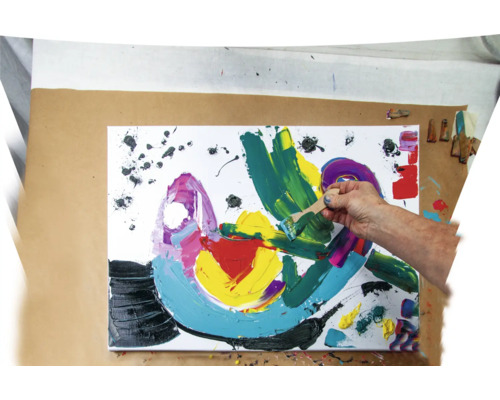 Une personne peint une peinture abstraite avec une spatule en bois sur une toile.