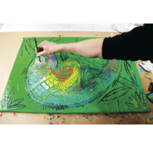 Une personne peint un motif de poisson coloré sur une toile.