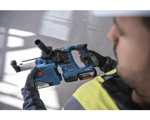 Un ouvrier tient un marteau perforateur bleu Bosch avec une batterie 18 volts.