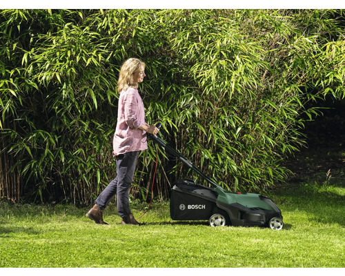 Femme utilise une tondeuse à gazon dans le jardin