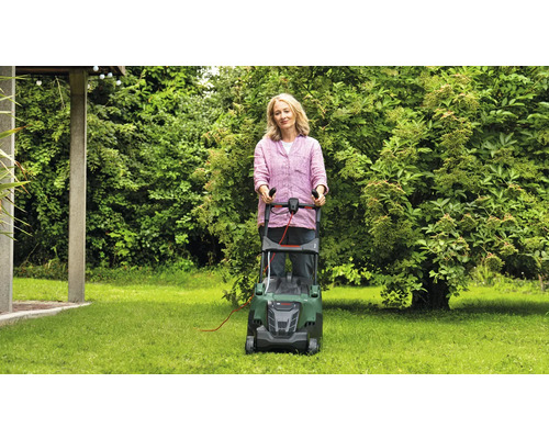 Femme utilisant une tondeuse à gazon dans le jardin.