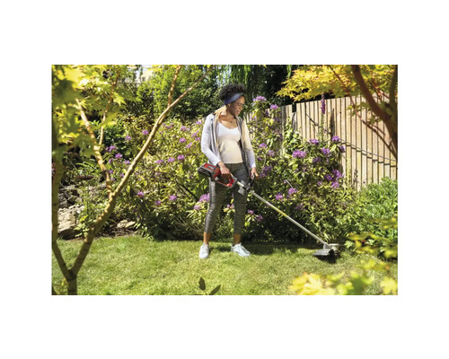 Frau arbeitet mit einem Akku-Rasentrimmer im Garten.