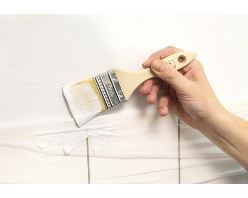 Hand streicht Wand mit einem Pinsel