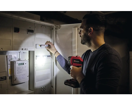 Un homme vérifie un boîtier à fusibles avec une lampe Einhell.