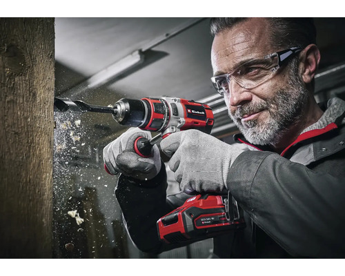 Ein Mann bohrt mit einem Einhell Akku-Bohrschrauber ein Loch in ein Holzstück.