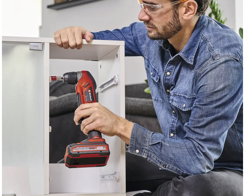 Mann arbeitet mit einem Einhell Akku-Bohrschrauber an einem Schrank