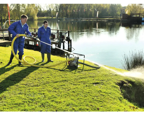 Deux ouvriers utilisent une pompe à eau au bord d''un lac pour le transfert d''eau.