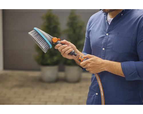 Une personne tient une brosse de lavage avec raccord d''eau dans sa main.