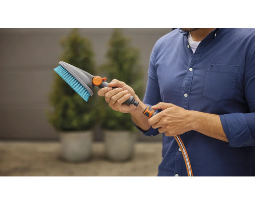 Un homme raccorde une brosse de lavage à un tuyau d''arrosage