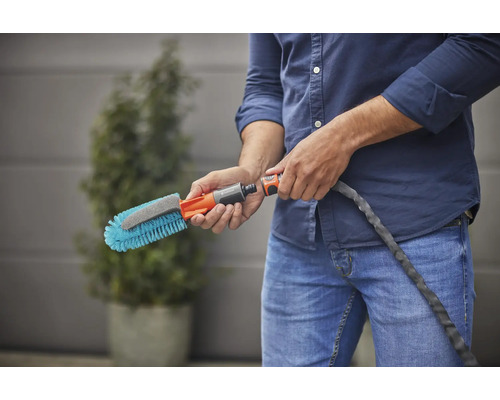 Une personne tient une brosse de lavage avec raccord d''eau.