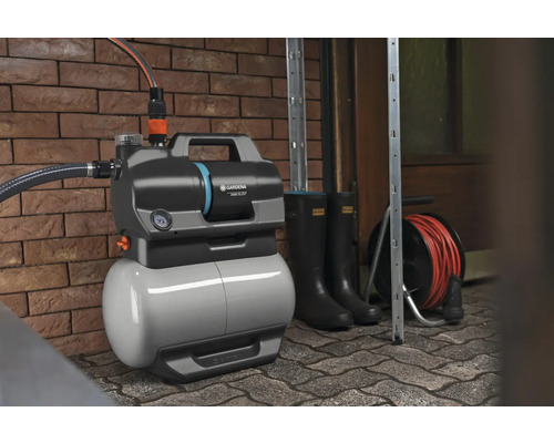 Pompe de jardin avec accessoires devant un mur de briques