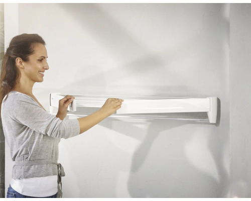 Frau bedient einen weißen, wandmontierten Wäschetrockner.