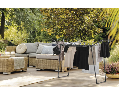 Séchoir à linge sur une terrasse avec coin salon et jardin en arrière-plan.