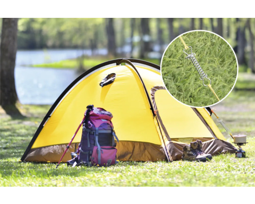 Tente jaune sur une prairie avec sac à dos, bâtons de randonnée et réchaud de camping. Gros plan sur le ressort de tente