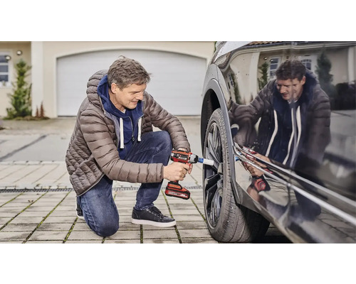 Un homme change une roue de voiture avec une clé à chocs sans fil