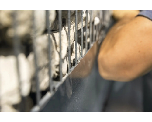 Gabione mit Steinen und Person bei der Installation