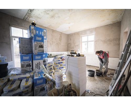 Heller Raum während Renovierung mit Dämmplatten, Kleber und Handwerker.