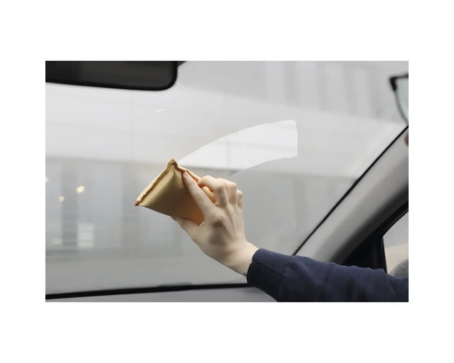 Une personne nettoie une vitre de voiture avec un chiffon de nettoyage.