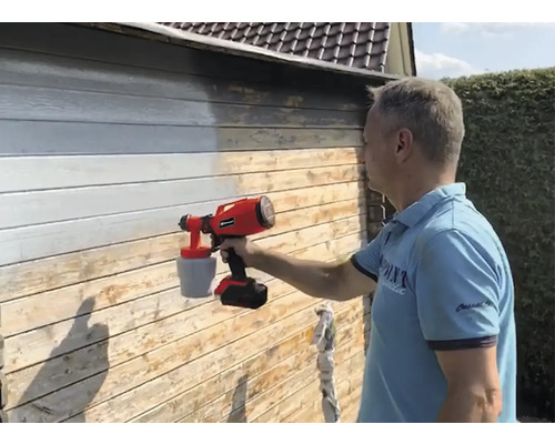 Mann streicht Holzwand mit Farbsprühsystem