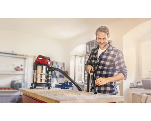 Mann benutzt einen Einhell Nass Trockensauger zum Reinigen einer Werkbank in einer Werkstatt.