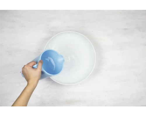 Une personne verse de l''eau d''un pichet dans un bol.