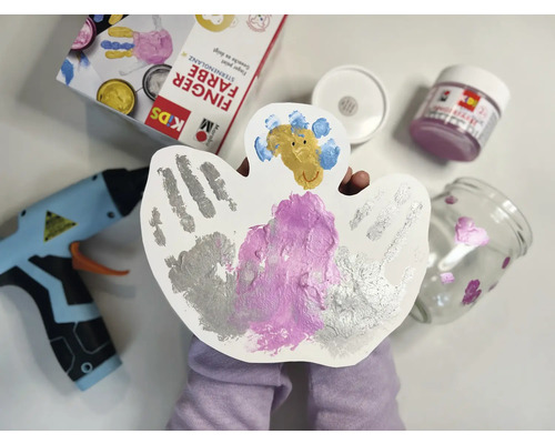 Bastelszene mit Fingerfarben, Klebepistole und bemalten Gegenständen