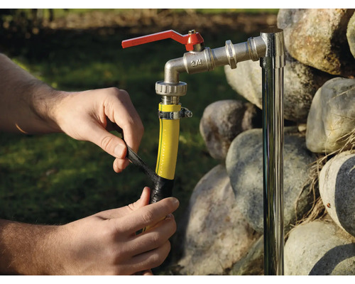 Person befestigt einen Gartenschlauch an einem Wasserhahn mit Isolierband.