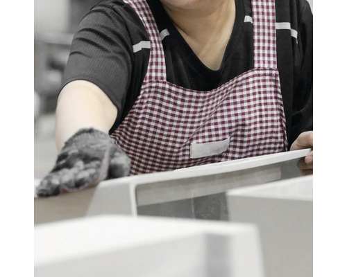 Eine Person mit Schürze bearbeitet ein Produkt.