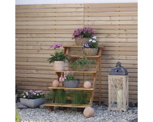Étagère à fleurs en bois avec diverses fleurs et décorations dans le jardin.