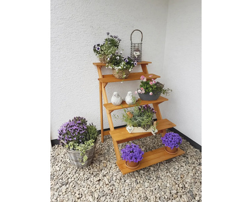 Étagère à plantes en bois avec des fleurs en pots et des paniers comme décoration de jardin.