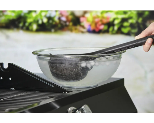 Nettoyage d''un panier de gril dans un bol d''eau glacée avec une pince à gril.