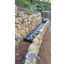 Installation d''un système de drainage le long d''un mur en pierre dans le jardin.