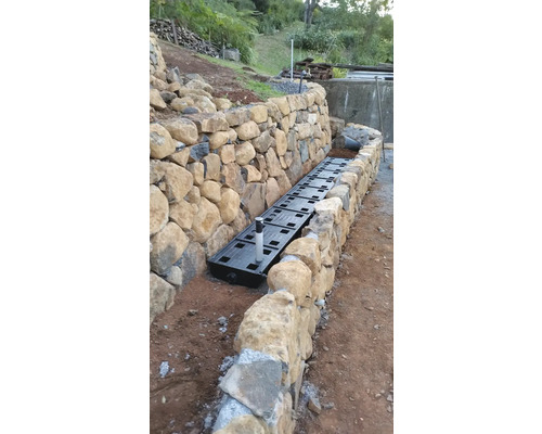 Installation d''un système de drainage le long d''un mur en pierre dans le jardin.