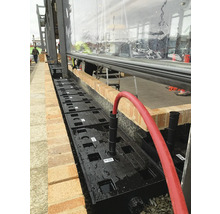 Installation d''un système de drainage des eaux pluviales avec des modules en plastique à côté d''un bâtiment.