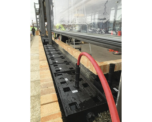 Installation d''un système de drainage des eaux pluviales avec des modules en plastique à côté d''un bâtiment.