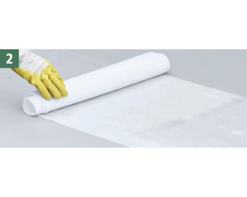 Une personne déroule une bâche de protection blanche pour protéger le sol.