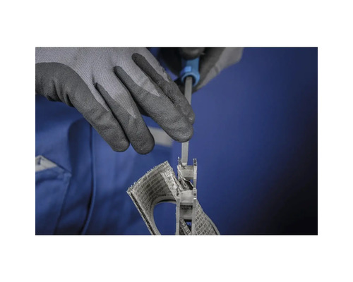 Eine Person, die mit Handschuhen arbeitet, befestigt ein Schleifgitter mit einem Werkzeug.