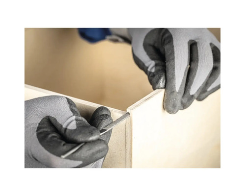 Un artisan ponce un bord en bois avec une râpe à bois