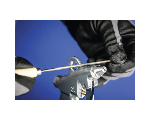 Düse einer Ausblaspistole wird mit einer Reinigungsnadel gereinigt.