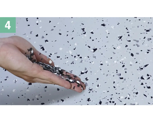 Une main saupoudre des copeaux décoratifs sur un sol.